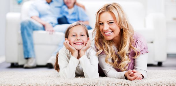 smiling mother and daughter laying on carpet